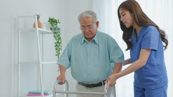 亚洲老年男性患者与护理人员进行物理治疗。有吸引力的专业护理人员女性帮助和支持年长的成熟男性在养老院护