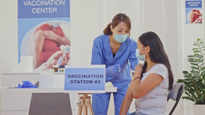 一名医护人员在接种中心为一名妇女注射新冠疫苗