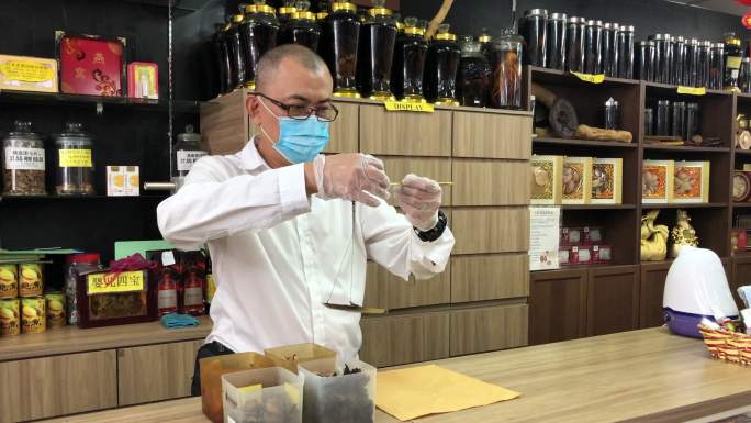 亚洲男性中国药剂师在中药店用传统秤称量草药
