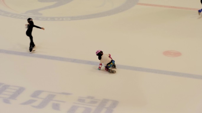 学滑冰的小女孩跌倒后重新站起来