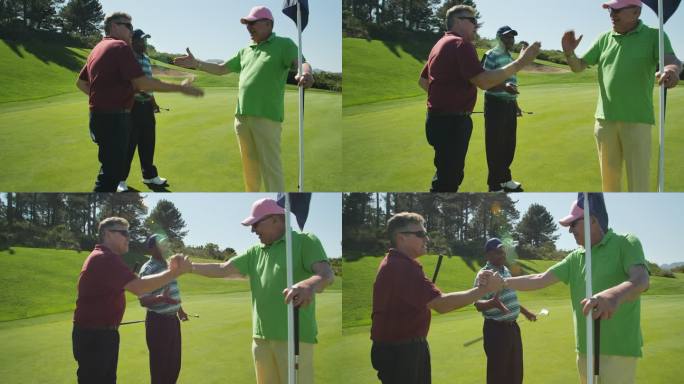 退休男性高尔夫球手在阳光明媚的高尔夫球场上庆祝和握手