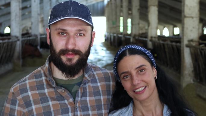 一对年轻农民夫妇幸福地在奶牛场工作的4k视频移动镜头。