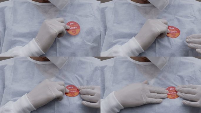 一名无法辨认的护士贴上贴纸的特写镜头：“我接种了新冠疫苗”