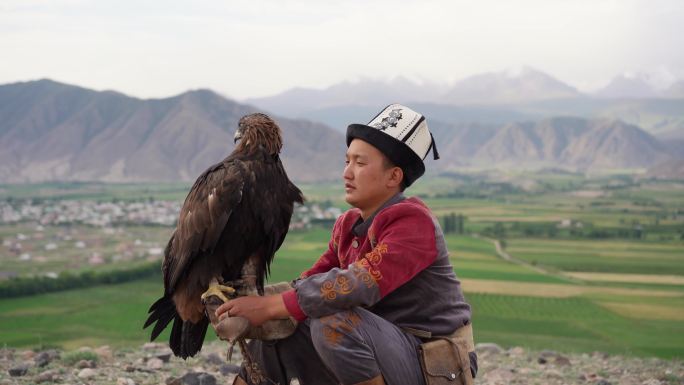 坐在吉尔吉斯斯坦山脉背景上的猎鹰者