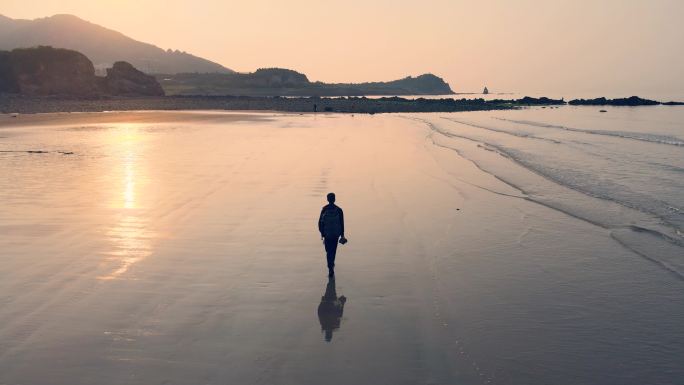 日出时在海滩上散步的人