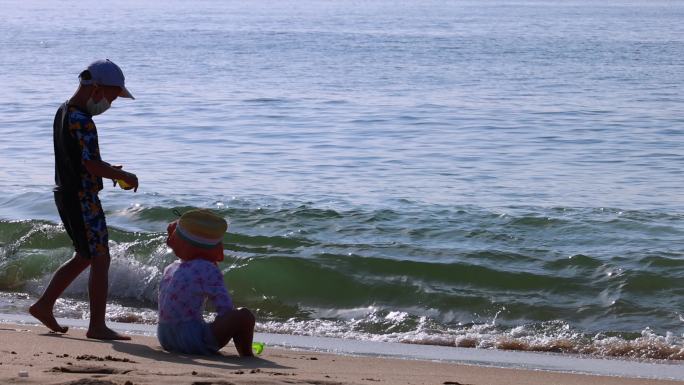 海边沙滩小女孩小男孩在晒太阳