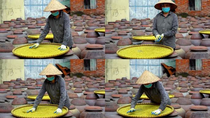 越南妇女在古老的房子院子里制作大豆酱和酱罐，这是一种由大豆制成的发酵豆酱，通常用于越南烹饪