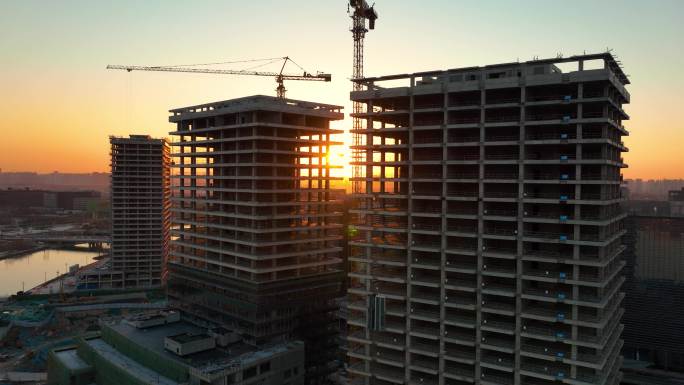 日落时建筑工地上的建筑起重机鸟瞰图