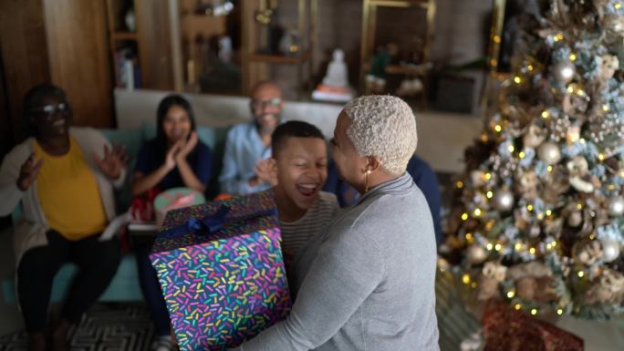 一个成熟的女人在家里给儿子送圣诞礼物（并玩猜谜游戏）