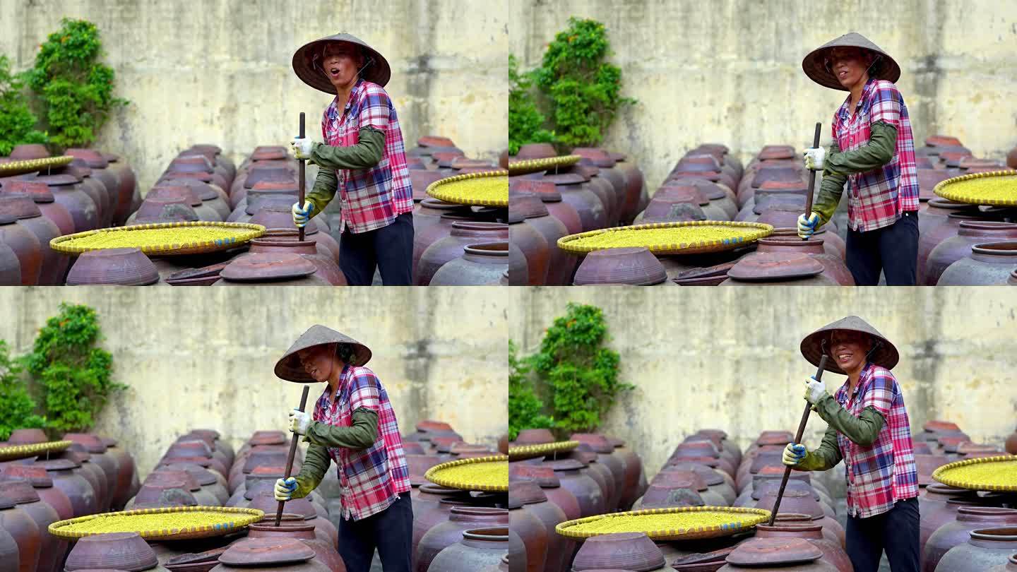 越南妇女在古老的房子院子里制作大豆酱和酱罐，这是一种由大豆制成的发酵豆酱，通常用于越南烹饪