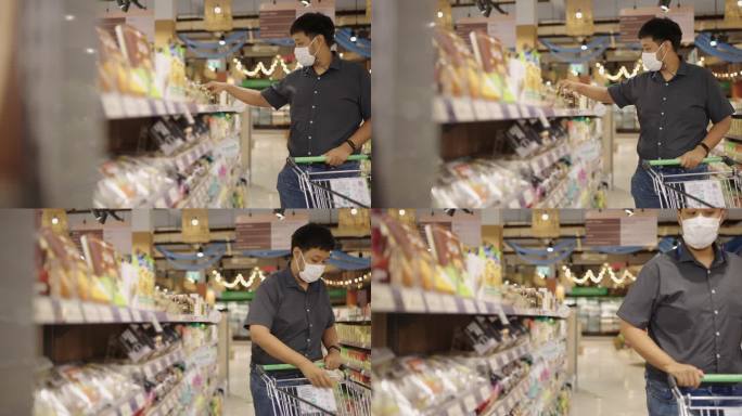 一个戴着防护面具的亚裔男子用购物车从过道上挑选小商品