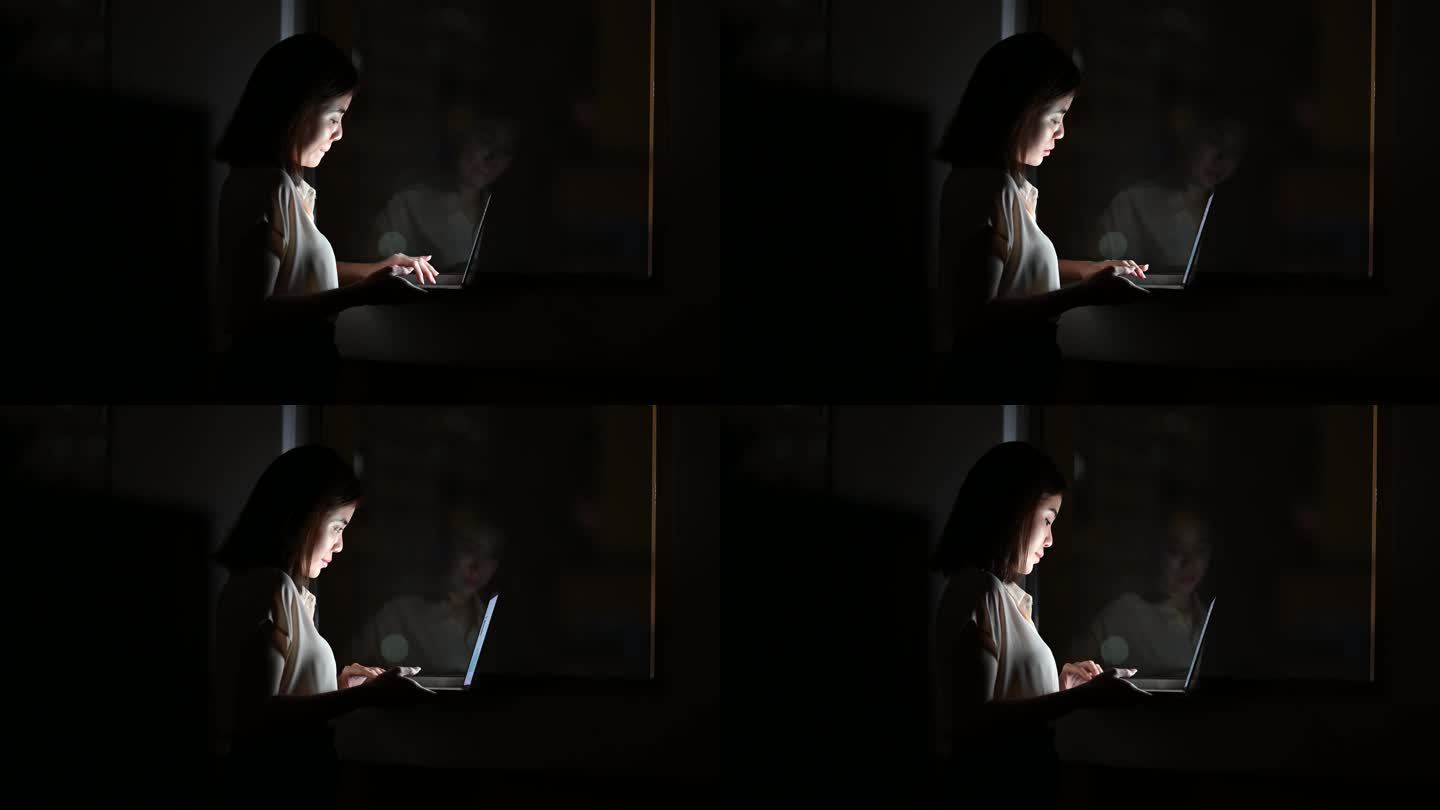 一位年轻的亚洲女商人在深夜工作时在办公桌前使用笔记本电脑。