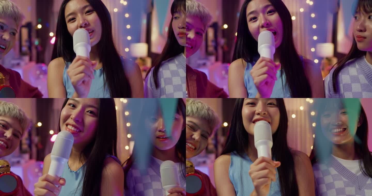 年轻的亚洲女性朋友唱卡拉OK的特写镜头，晚上在多彩的家庭聚会上玩得很开心。