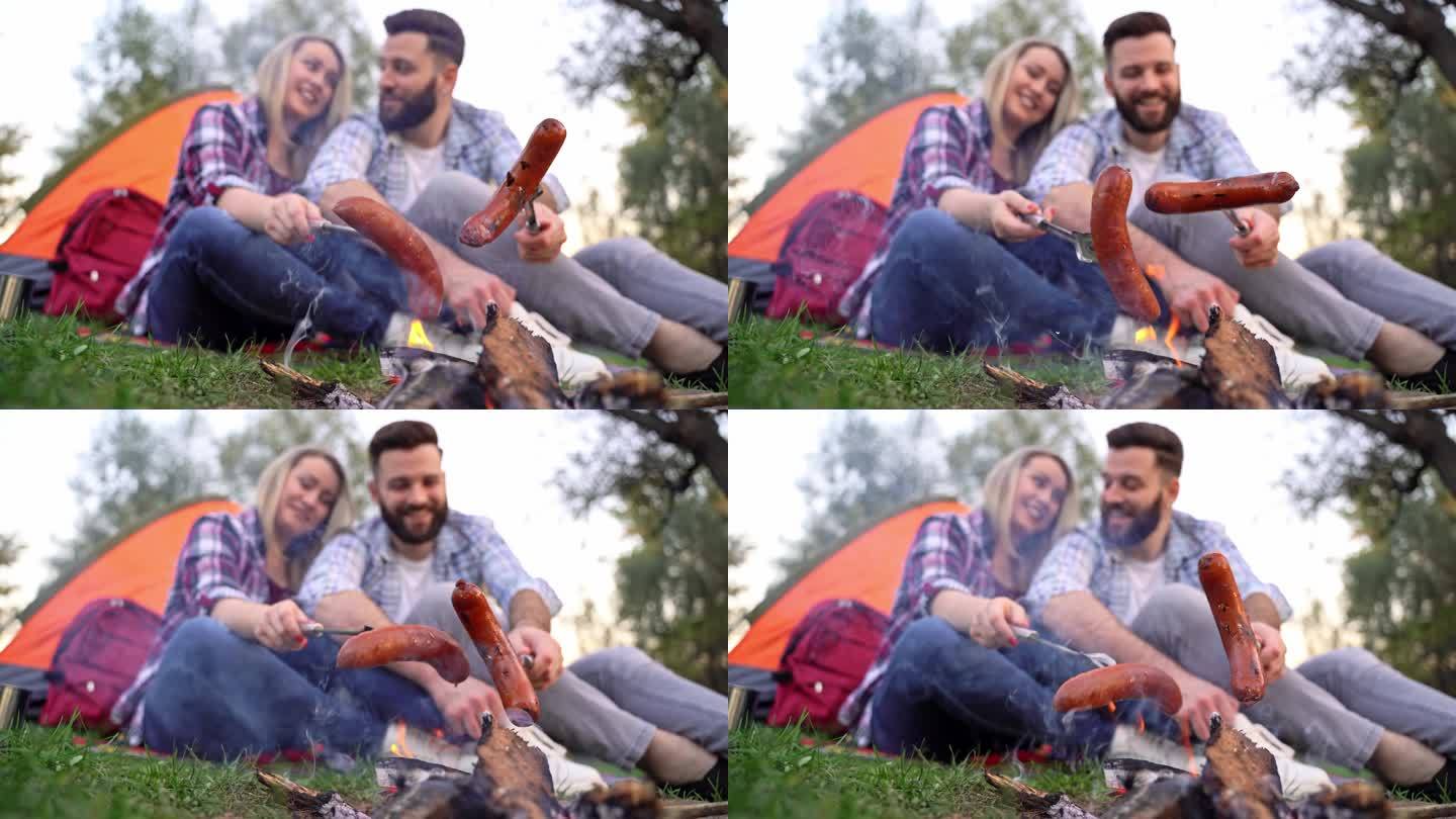 一对夫妇在篝火上烤香肠