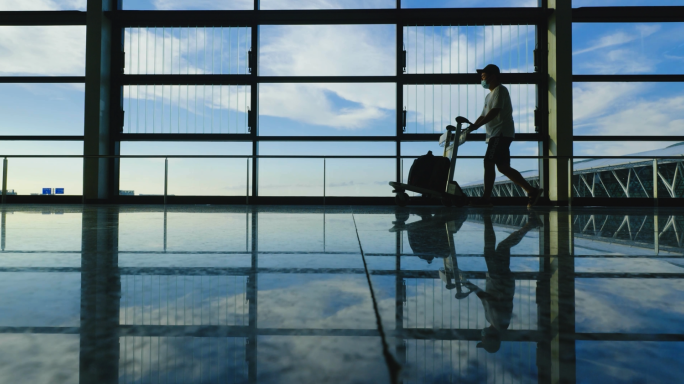 机场推行李登机安检机场大厅人流逆光剪影