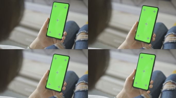 女人在沙发上使用绿色屏幕的智能手机