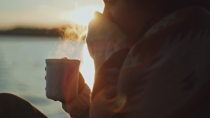 斯洛-莫，一位年轻女子，裹着毯子，在夕阳下的帆船甲板上喝茶时打喷嚏