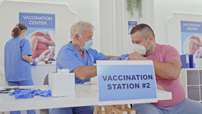 一名医护人员在接种中心为一名男子注射新冠疫苗