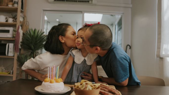 泰国父母在家里的生日派对上亲吻他们的女孩。
