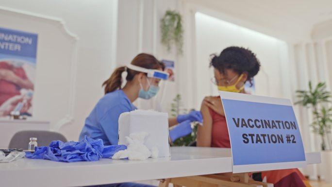 戴着防护面罩的黑人妇女在现代新冠疫苗接种中心接种疫苗