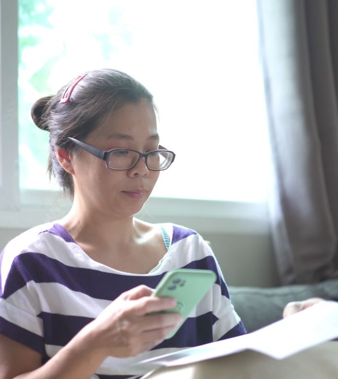 亚洲女性在家通过智能手机支付财务账单
