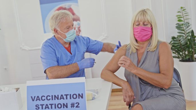 一名医护人员在接种中心为一名妇女注射新冠疫苗