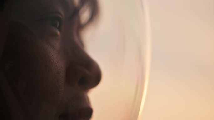 一名亚裔中国中年女宇航员从太空船的窗户望着地球日出