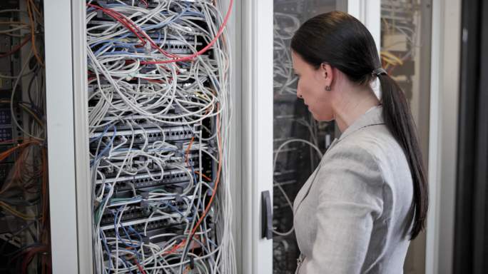 一个女人在服务器室里的电缆乱七八糟的情况下紧张地走开了
