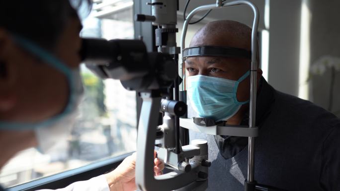 验光师戴着防护面罩检查病人的眼睛