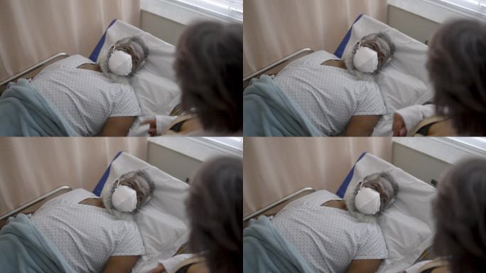 医生在医院病房与患者交谈-戴防护面罩