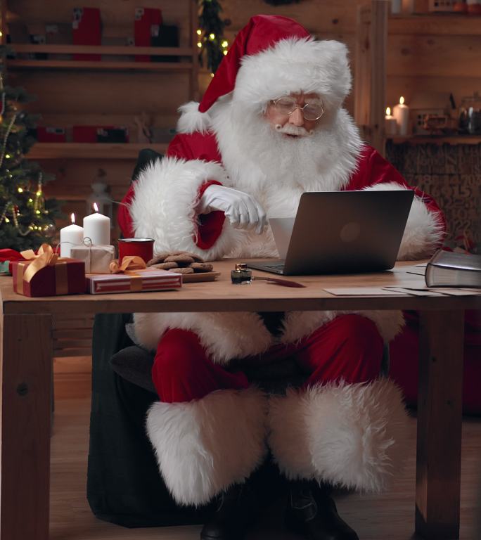 圣诞老人打开装有信件的信封，在笔记本电脑上做上标记