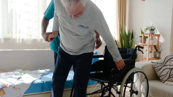 在疗养院轮椅上帮助老人的男护士