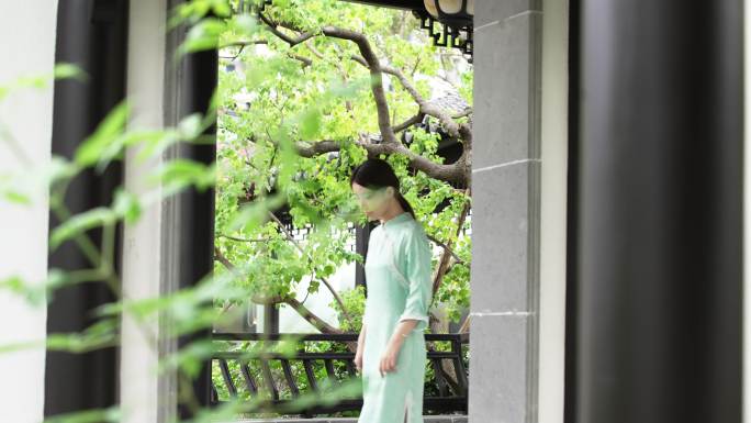 年轻旗袍女子步行穿过中式合院门廊