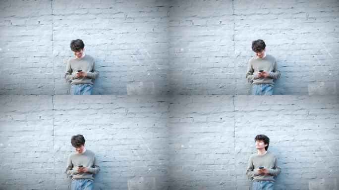 一名年轻男子倚靠灰色墙壁使用智能手机的4k视频片段