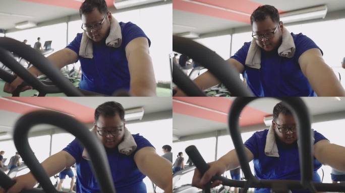 一名超重男子在健身房健身课上骑着固定自行车不屈不挠地骑着自行车。