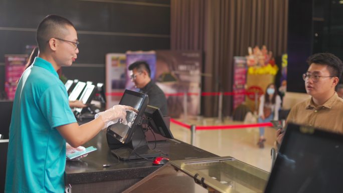 亚洲华人青少年在电影院电影放映前购买电影票、爆米花和饮料