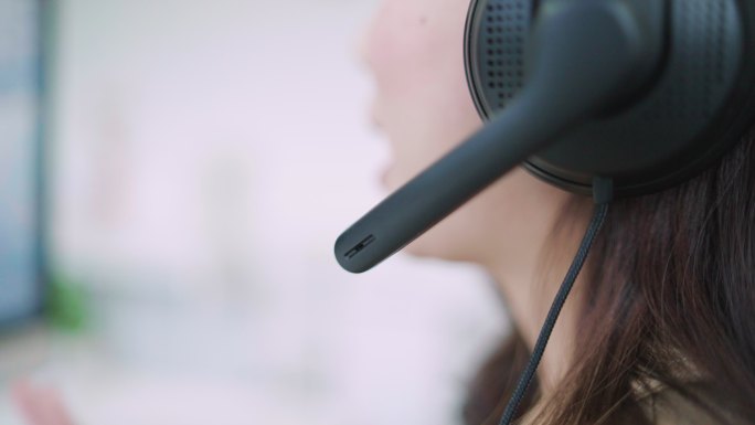 呼叫中心的一位年轻女士正在通过电话帮助一位客户