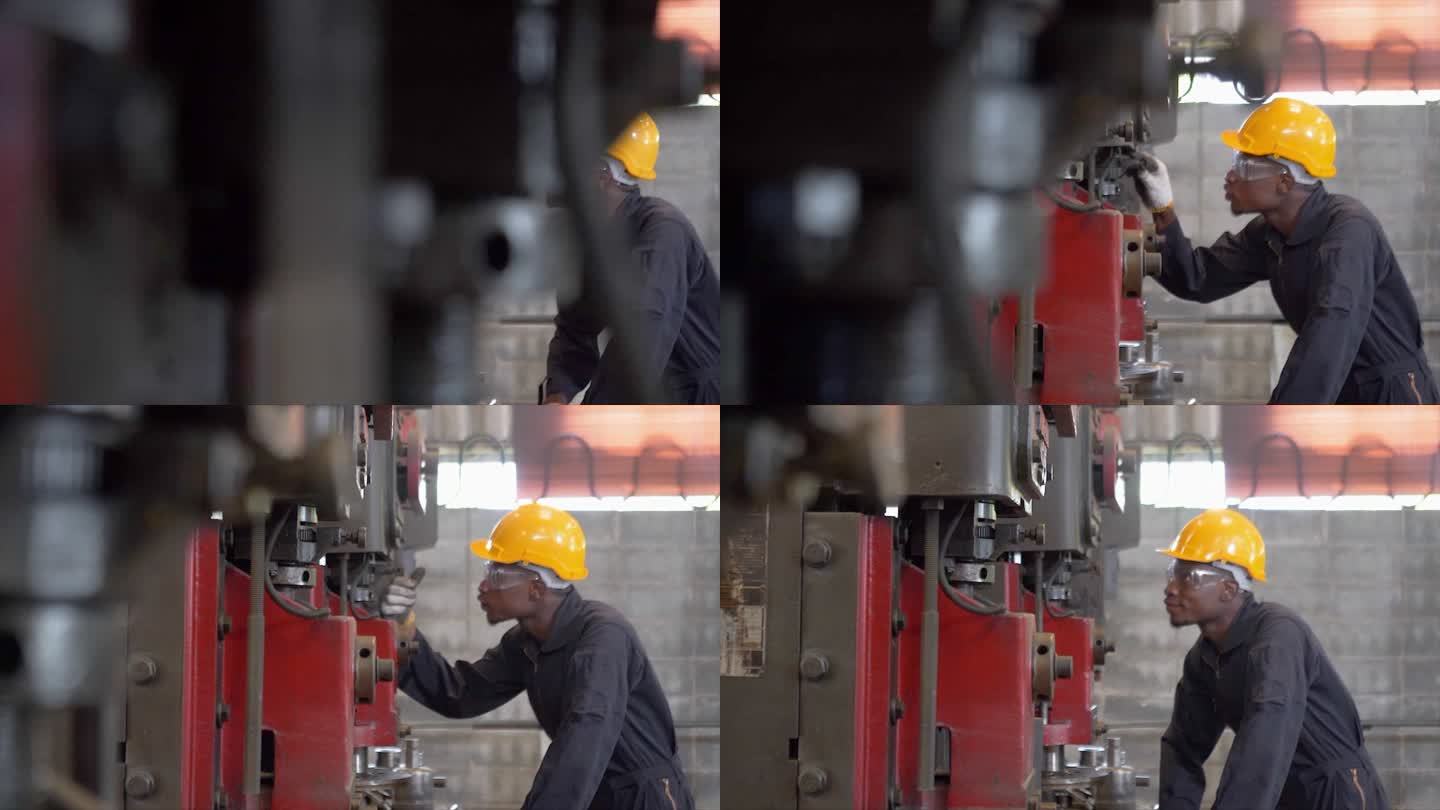 在工厂特写镜头中，一名在控制面板上工作的非洲裔美国人与一台工业机器一起工作。在工业机械中，男性工程师
