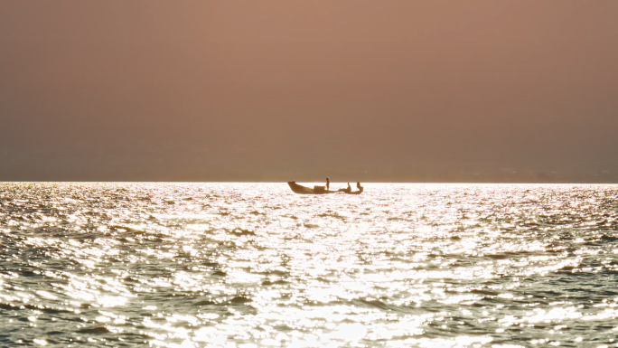 海边落日下的渔船渔民黄昏湖面波光粼粼