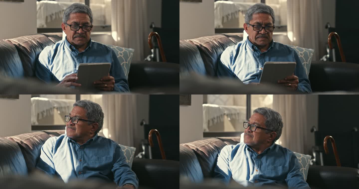 一位老人在家里沙发上使用数字平板电脑，看起来很有思想的4k视频片段