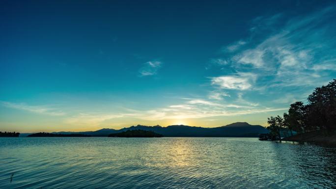 日落时山和湖的宁静场景，从白天到黄昏的延时视频