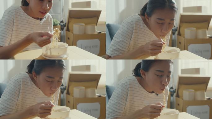 一位年轻的亚洲妇女搬家的特写镜头，打开包装后坐在沙发上吃方便面。