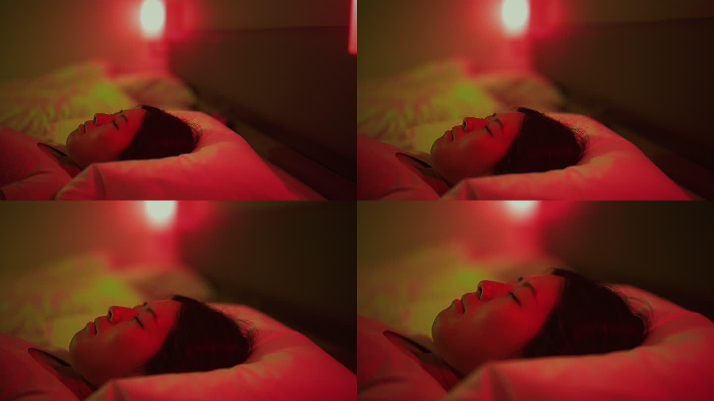 一个年轻的女人被红色和绿色的霓虹灯照亮，在家里卧室的床上休息