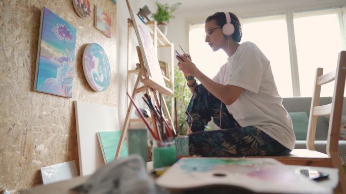 女艺术家，一名在线学习者，在手机上学习教程，并复制绘画