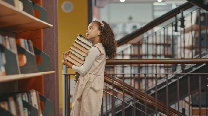 一个小女孩独自在图书馆里。一个小孩正在做研究。可爱的孩子在图书馆做她的学校作业。