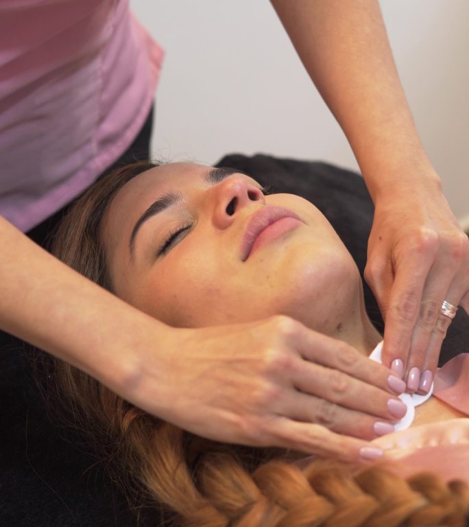职业女性美容师在客户脸上进行美容治疗