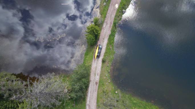 在土路上驾驶皮划艇的汽车鸟瞰图。当地的公路旅行。