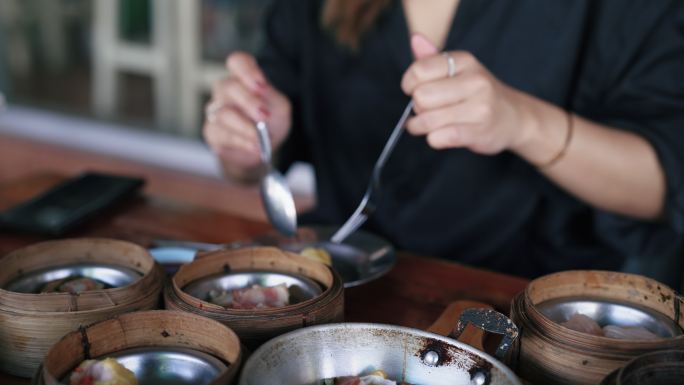 一个亚洲女人在用酱汁调味之前把一个虾饺放进她的盘子里。