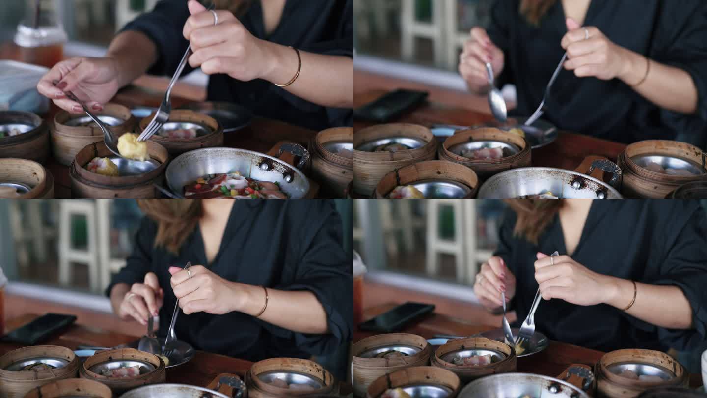 一个亚洲女人在用酱汁调味之前把一个虾饺放进她的盘子里。