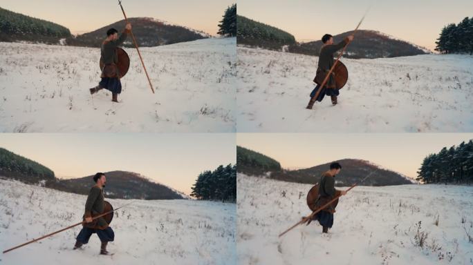 一位中世纪战士在日落时手持盾牌和长矛行走在白雪覆盖的草地上